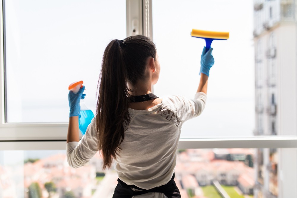 Office cleaner cleaning glass window using squeeze